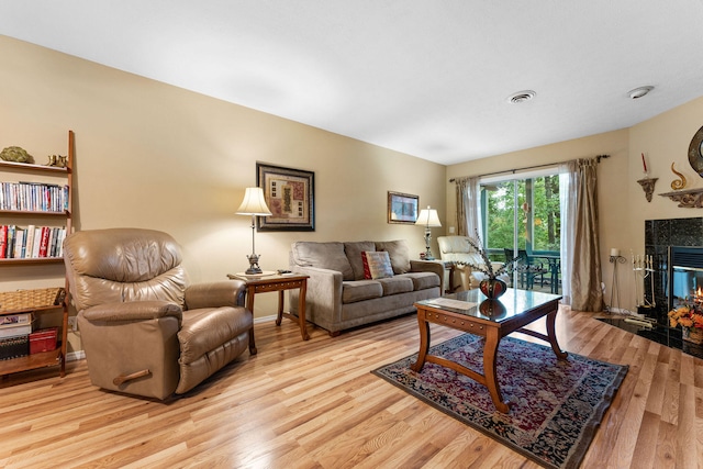 living room featuring a tiled fireplace and light hardwood / wood-style floors