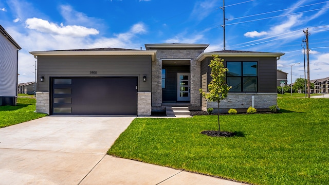 prairie-style home featuring a garage, stone siding, a front lawn, and concrete driveway
