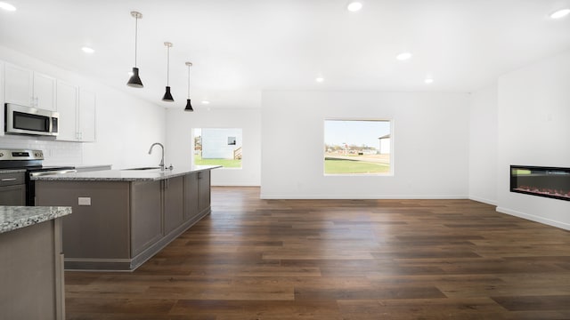 kitchen with sink, white cabinetry, hanging light fixtures, stainless steel appliances, and light stone counters