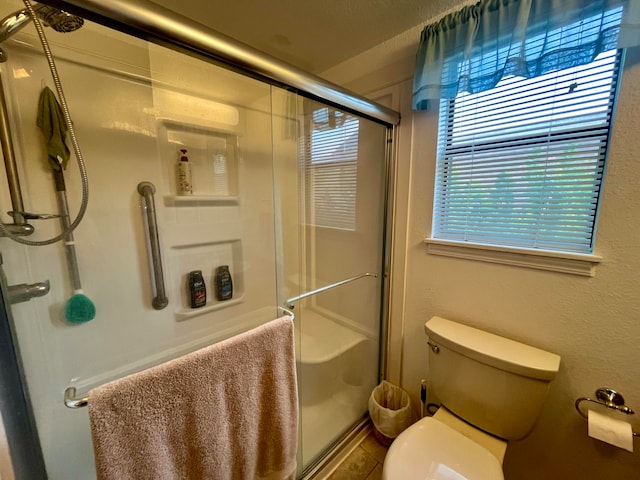 bathroom featuring an enclosed shower, a wealth of natural light, and toilet