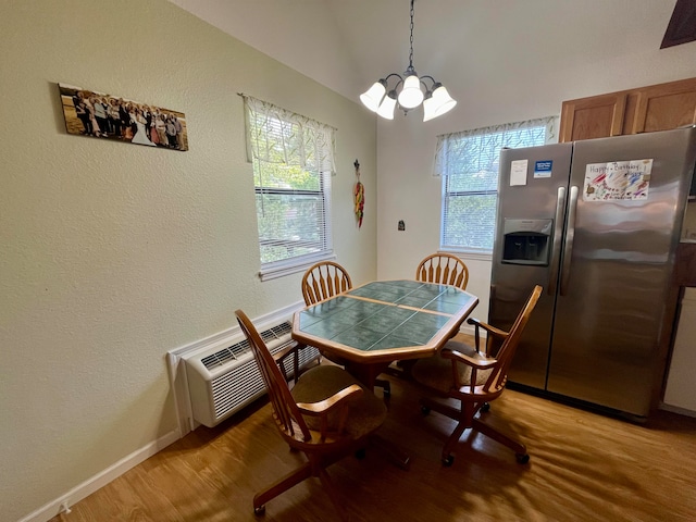 dining area with an inviting chandelier, light hardwood / wood-style flooring, vaulted ceiling, and an AC wall unit