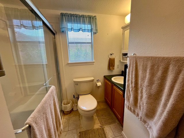 bathroom with tile patterned flooring, toilet, a shower with shower door, vanity, and a textured ceiling