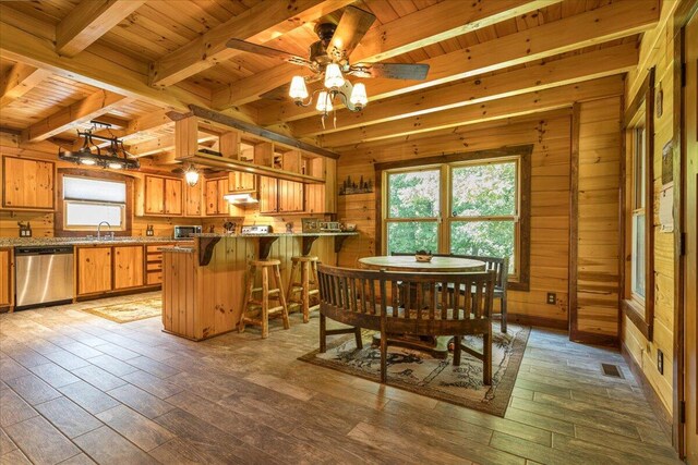 dining room featuring beam ceiling, visible vents, wood ceiling, wooden walls, and wood finished floors