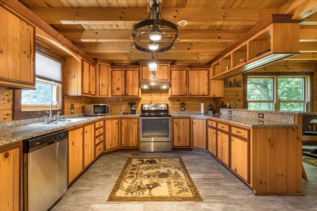 kitchen with appliances with stainless steel finishes, a sink, a peninsula, beamed ceiling, and under cabinet range hood