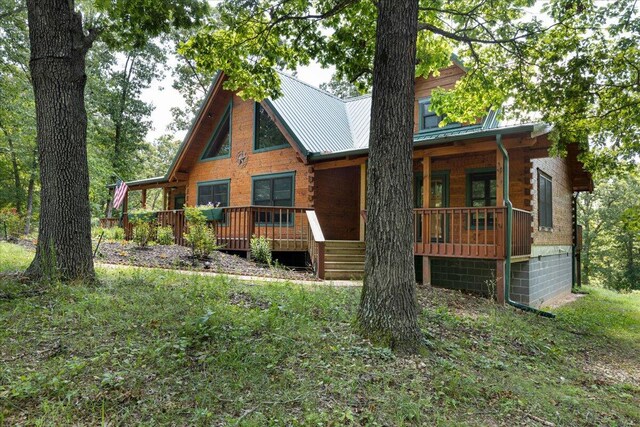 back of house featuring a standing seam roof, log siding, and metal roof