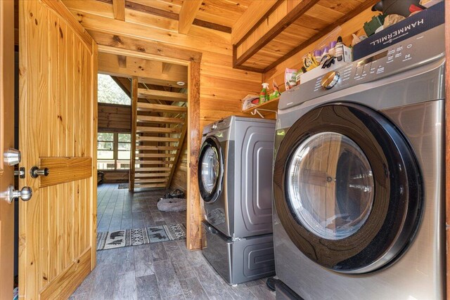 laundry area featuring laundry area, wooden walls, wood finished floors, and washing machine and clothes dryer