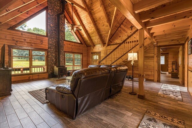 living area featuring wooden ceiling, hardwood / wood-style flooring, a wood stove, wood walls, and beam ceiling