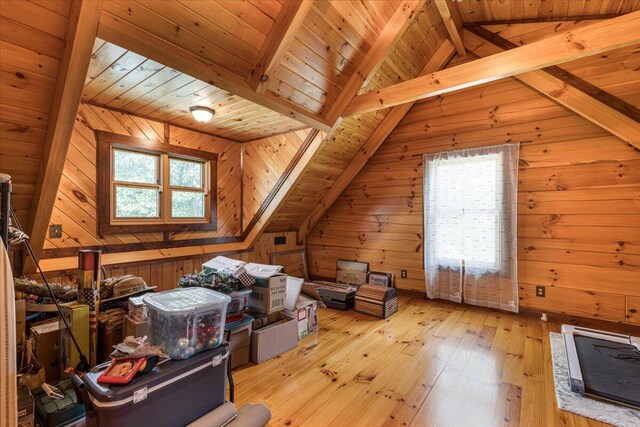 additional living space with vaulted ceiling with beams, wooden walls, wooden ceiling, and light wood-style floors