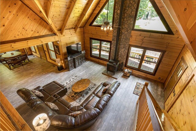 unfurnished living room featuring wood-type flooring, wooden walls, high vaulted ceiling, and beamed ceiling