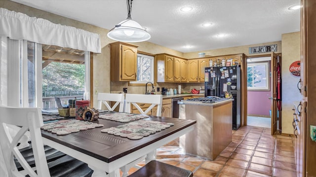 3166 W Seminole St, Springfield, MO 65807 - kitchen featuring black fridge with ice dispenser, a kitchen island, a textured ceiling, light countertops, and decorative light fixtures