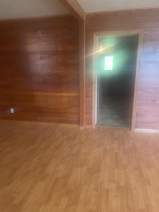 empty room with wooden walls and light wood-style flooring