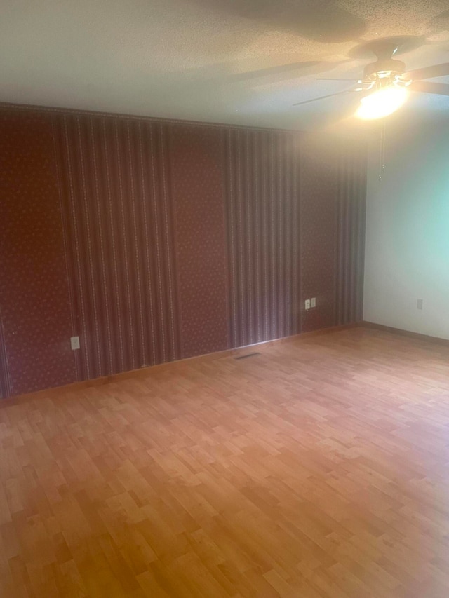 unfurnished room featuring ceiling fan, a textured ceiling, and light wood-type flooring