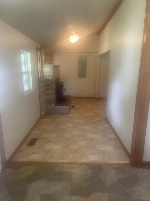 hall featuring baseboards, visible vents, vaulted ceiling, and electric panel