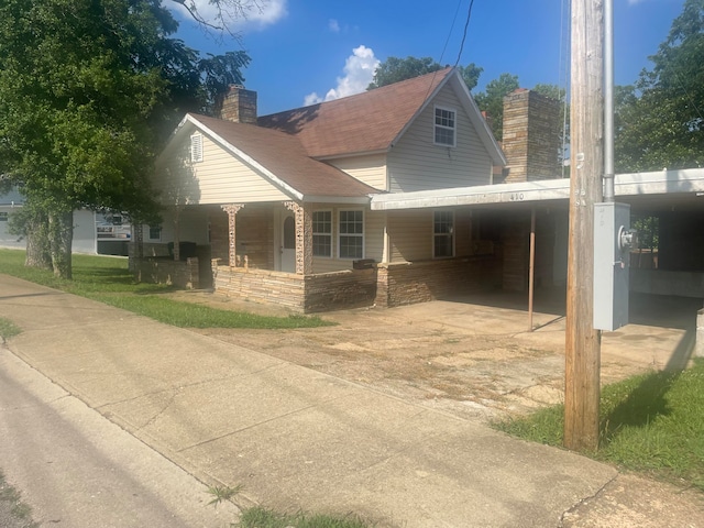 view of side of home featuring covered porch and a carport