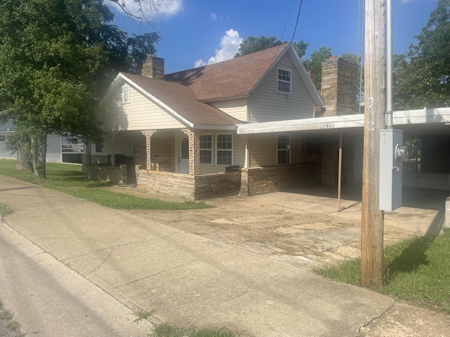 view of front of home featuring a chimney, driveway, a porch, and an attached carport