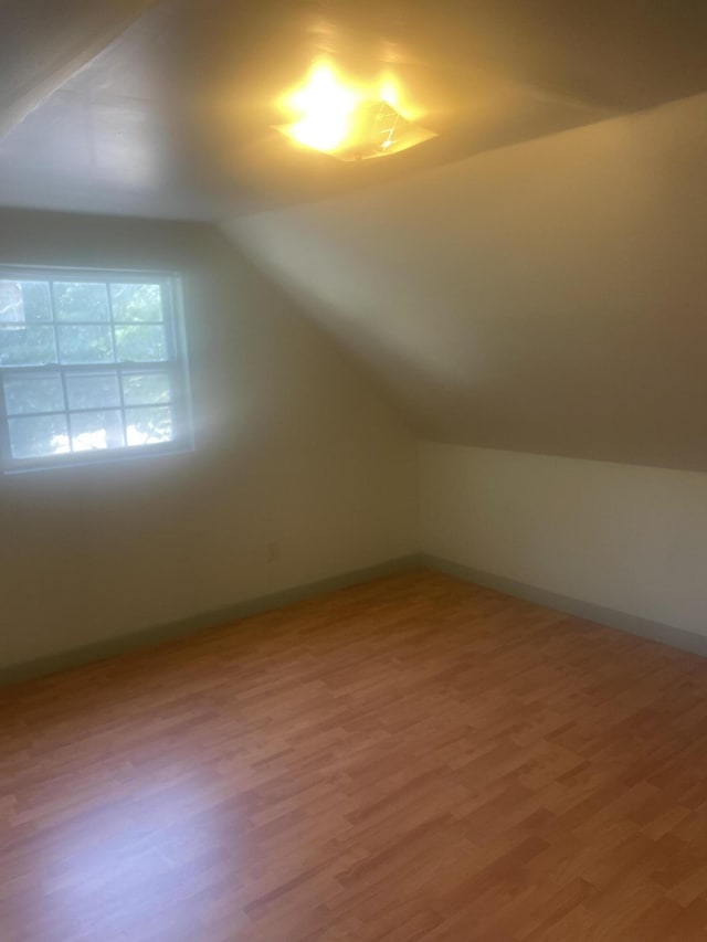 bonus room with lofted ceiling, baseboards, and wood finished floors