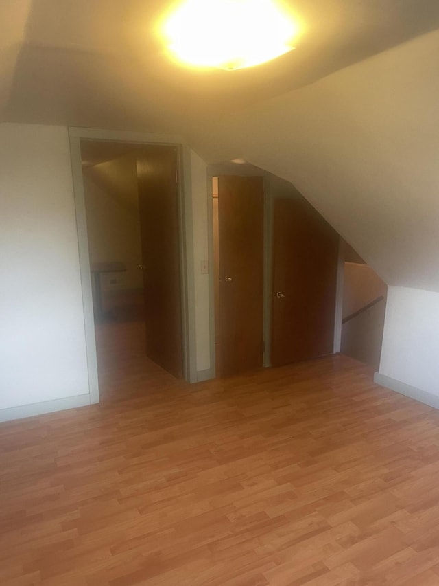 bonus room with vaulted ceiling, baseboards, and light wood-style floors