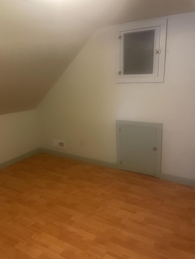 additional living space with light wood-style floors, lofted ceiling, and baseboards