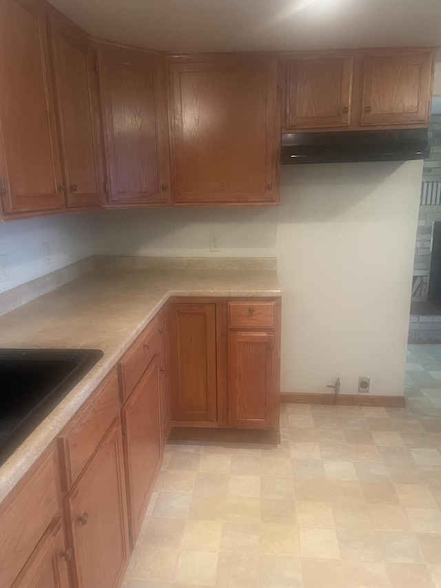 kitchen with light floors, brown cabinetry, a sink, and light countertops