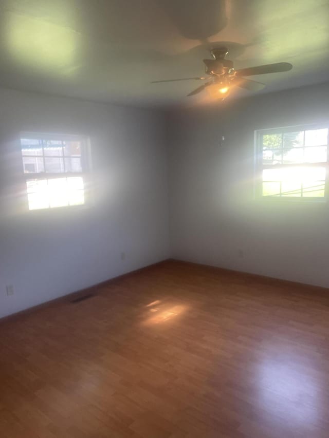 empty room with baseboards, a ceiling fan, and wood finished floors