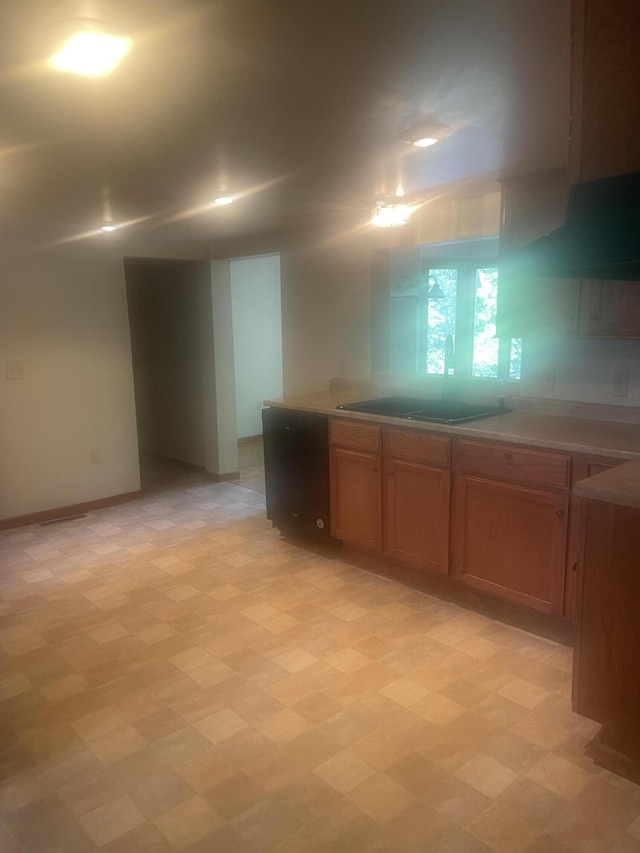kitchen with light countertops, black electric cooktop, brown cabinetry, and light floors