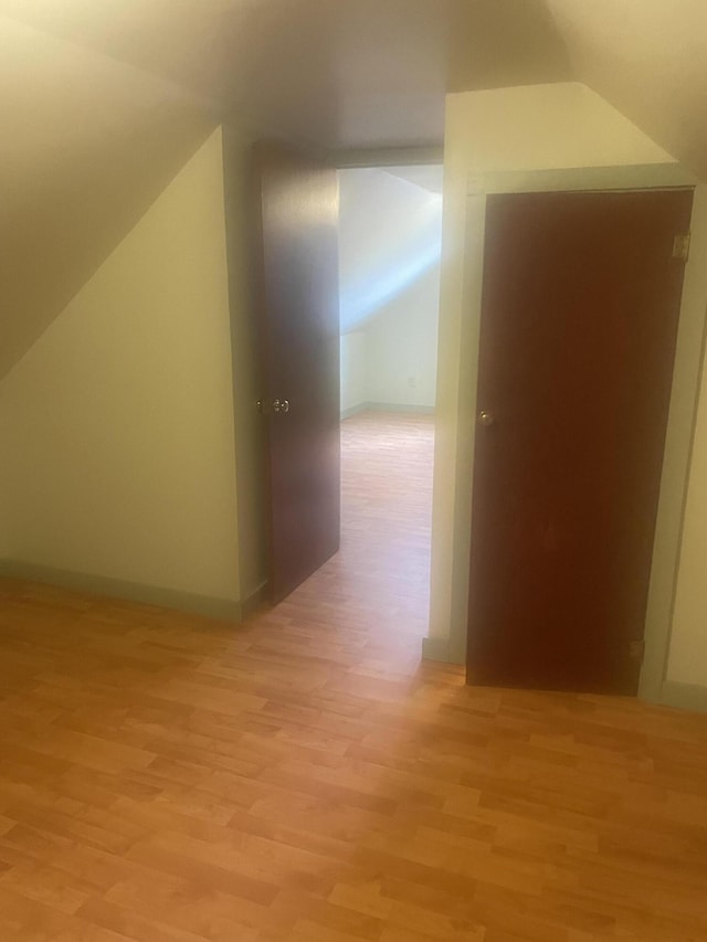 additional living space with vaulted ceiling and light wood-type flooring