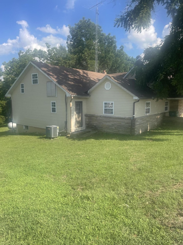 view of front of property featuring central air condition unit, a front lawn, and stone siding