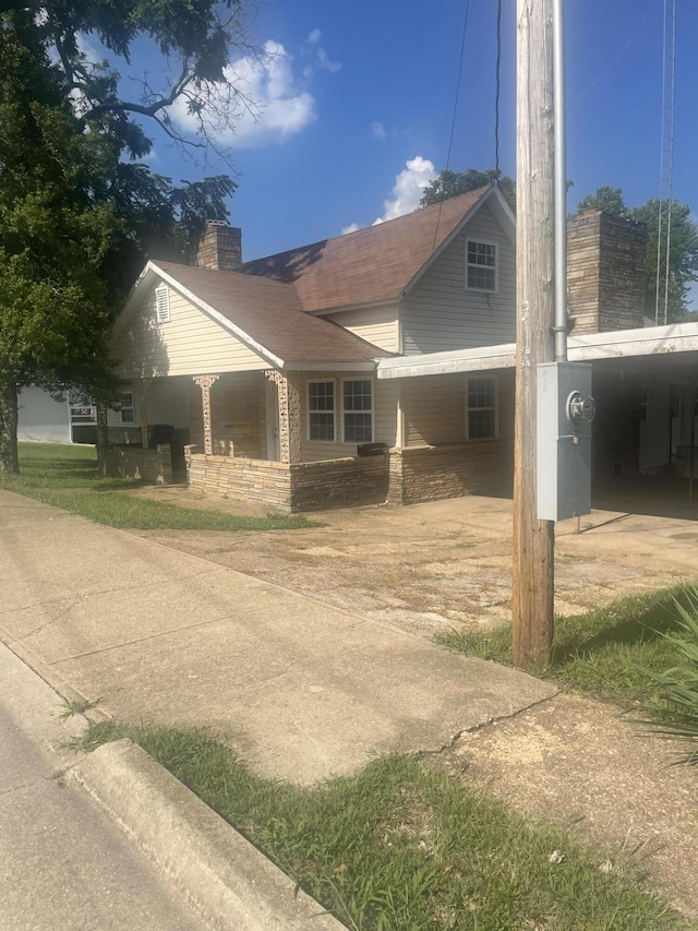 view of property exterior featuring a chimney and covered porch