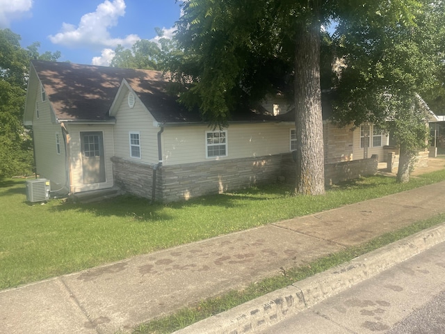 view of home's exterior with a lawn, central AC unit, and a shingled roof
