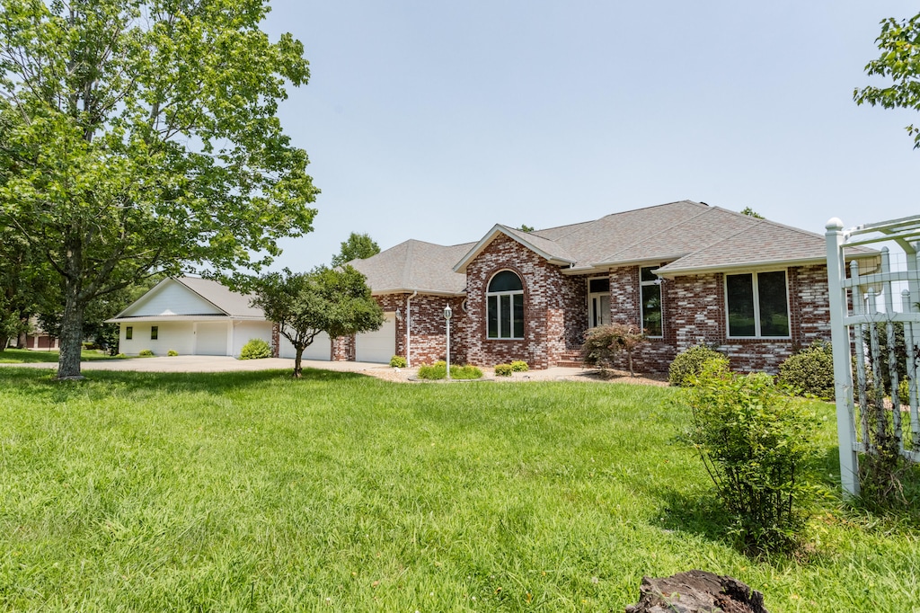 ranch-style home with a garage, driveway, brick siding, and a front yard