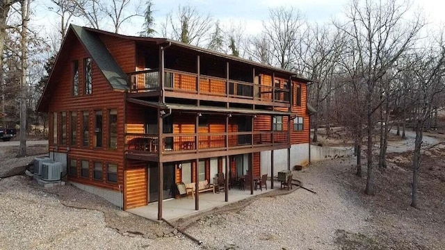 rear view of property featuring cooling unit, a balcony, and a patio area