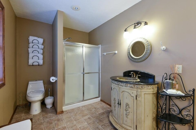 bathroom with vanity, a shower with door, and toilet