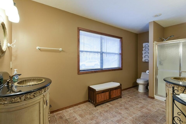 bathroom with toilet, vanity, and a shower with shower door