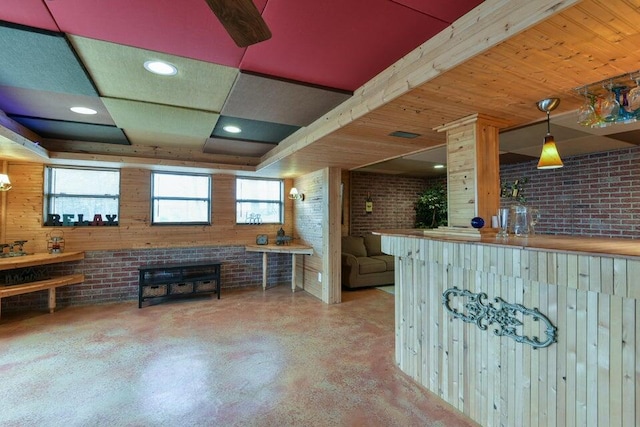 kitchen featuring brick wall, pendant lighting, and concrete flooring