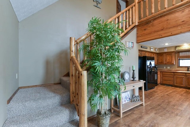 staircase featuring carpet floors, high vaulted ceiling, sink, and a textured ceiling