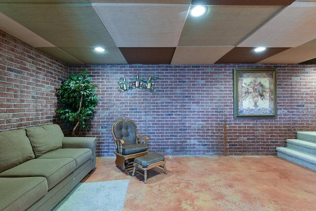 carpeted living room with brick wall