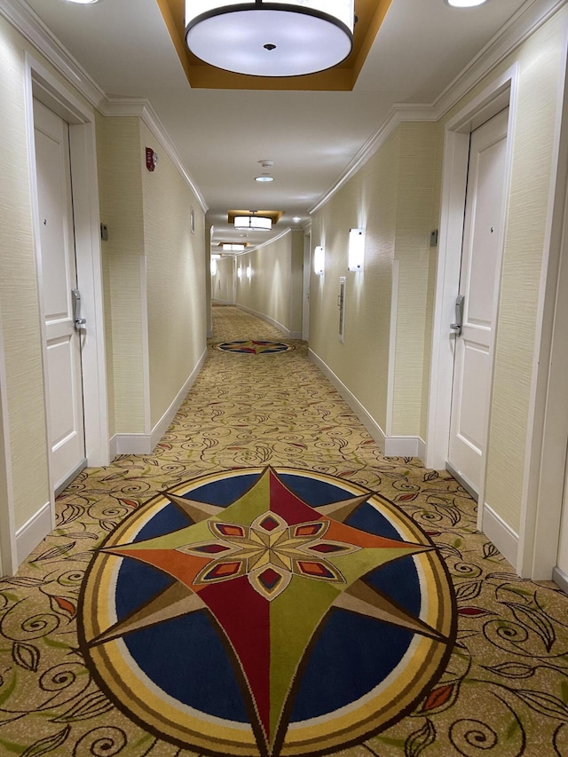 hall with ornamental molding, baseboards, and light carpet