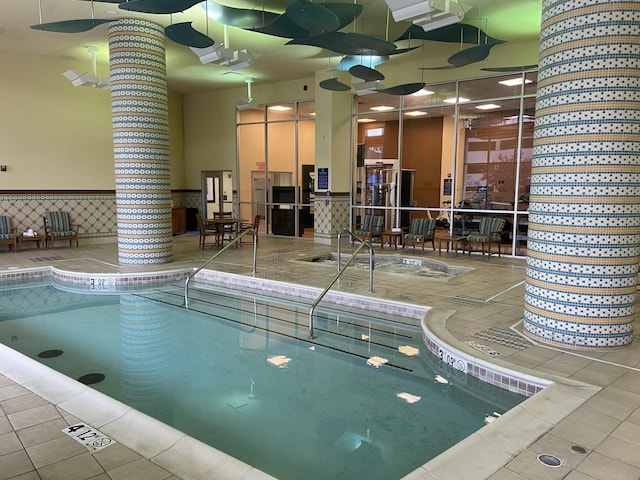 community pool featuring an indoor in ground hot tub and ornate columns
