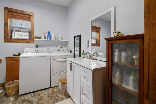 clothes washing area with washing machine and clothes dryer, cabinet space, and a sink