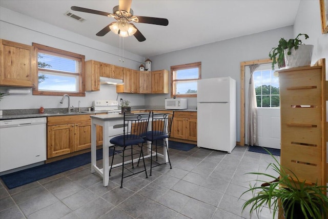 kitchen featuring visible vents, a sink, white appliances, dark tile patterned flooring, and ceiling fan