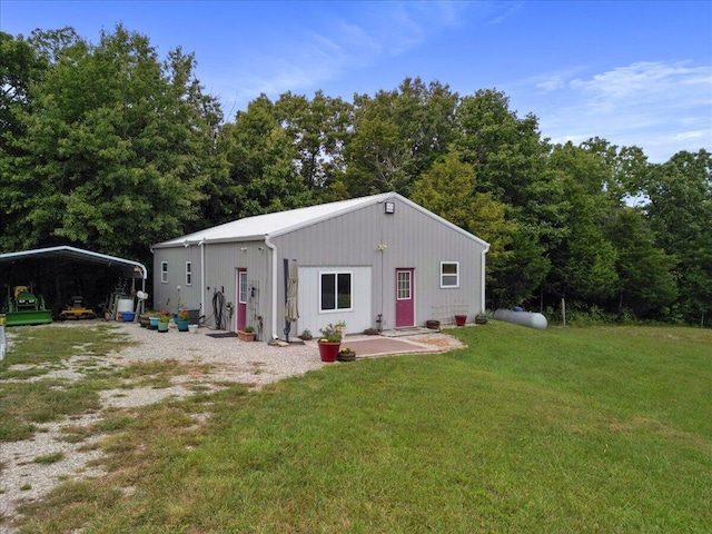 back of property featuring a detached carport and a lawn