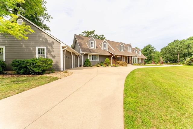 cape cod house featuring a garage and a front lawn