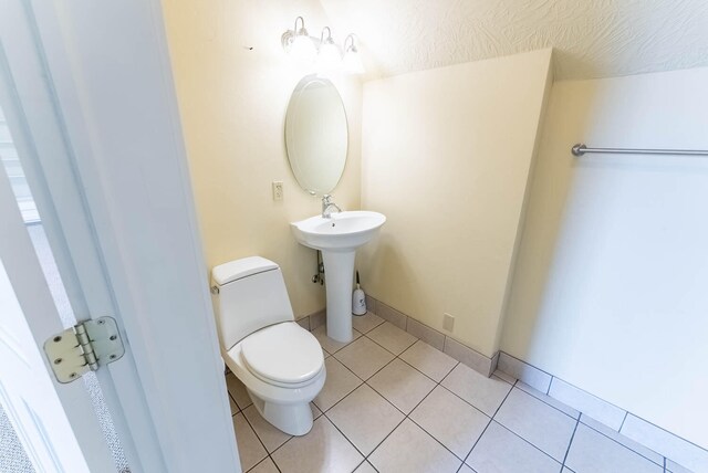 bathroom featuring a textured ceiling, tile patterned flooring, toilet, and sink