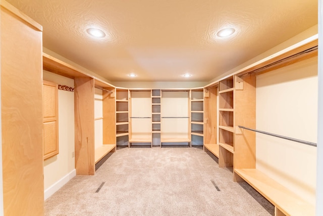 walk in closet featuring light colored carpet