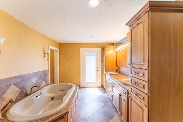 bathroom with a textured ceiling, tile patterned floors, vanity, and a bathing tub