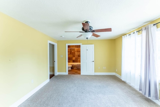 unfurnished bedroom featuring carpet floors, connected bathroom, a textured ceiling, and ceiling fan