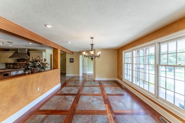 unfurnished dining area with a notable chandelier and a textured ceiling