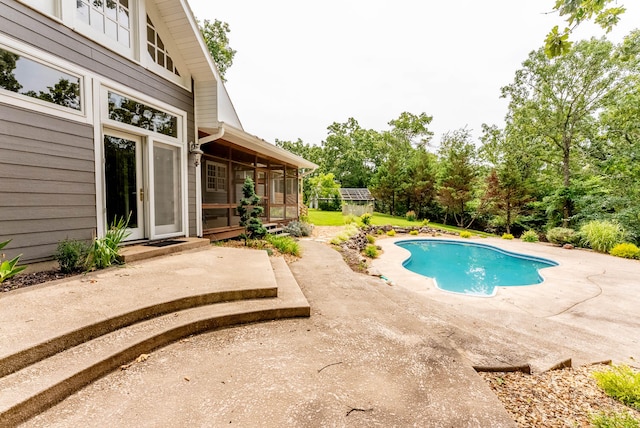 view of swimming pool featuring a sunroom and a patio area