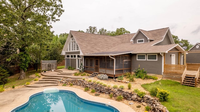 rear view of house featuring a yard, a sunroom, a patio area, and a swimming pool side deck