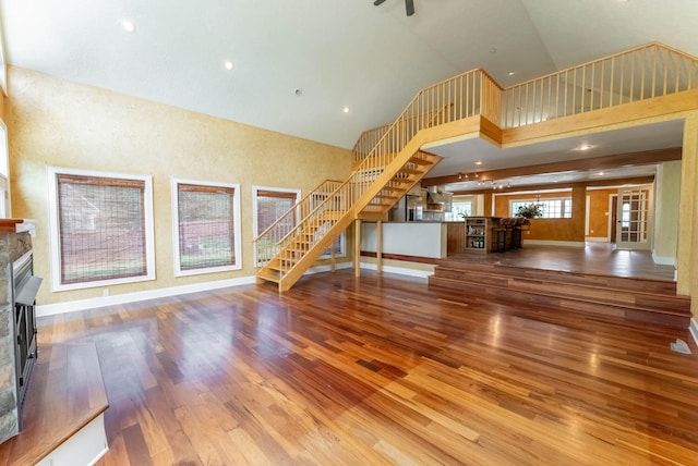 unfurnished living room with a stone fireplace, hardwood / wood-style flooring, and high vaulted ceiling